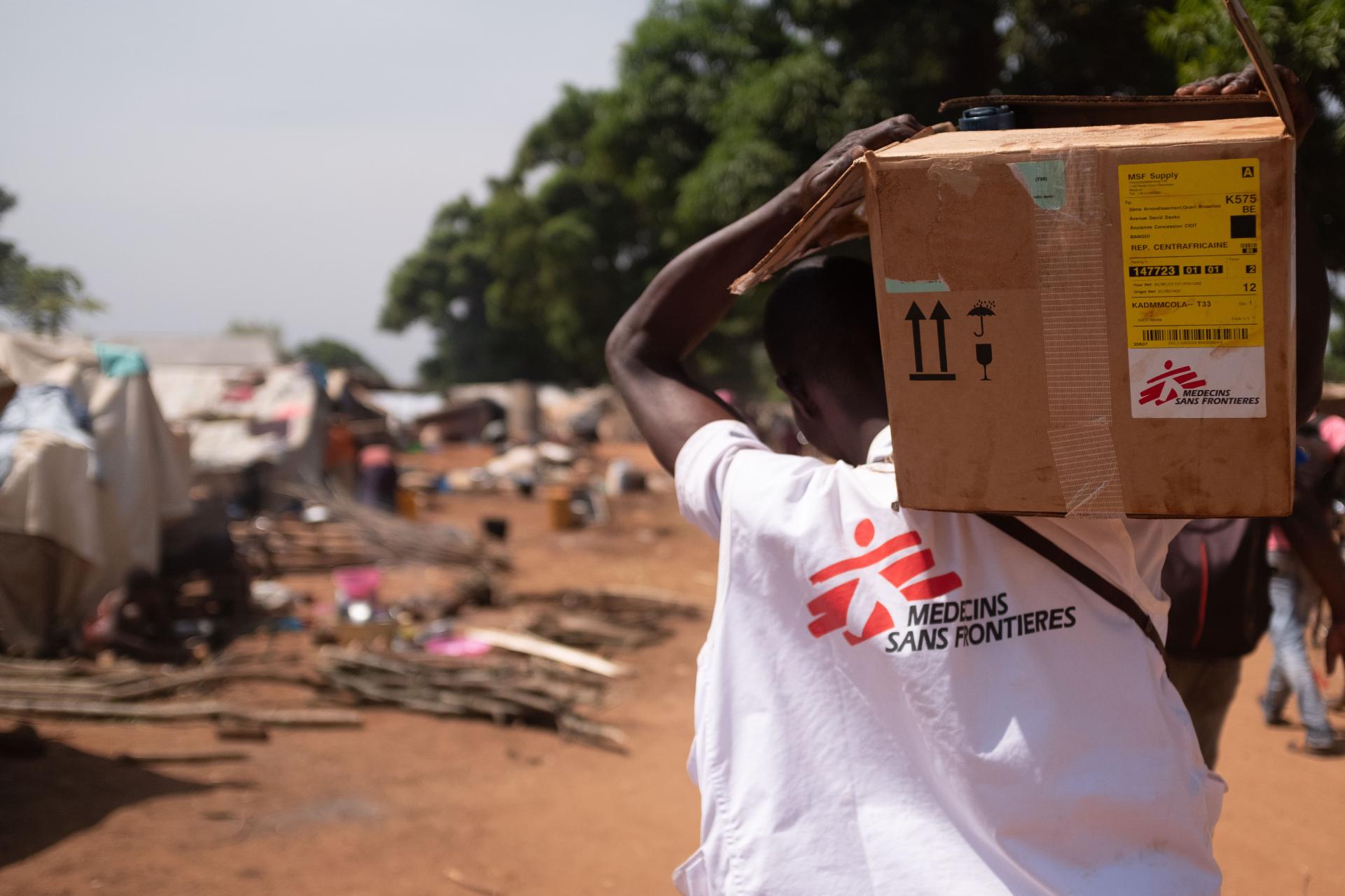 MSF team member carrying medical supplies to a community